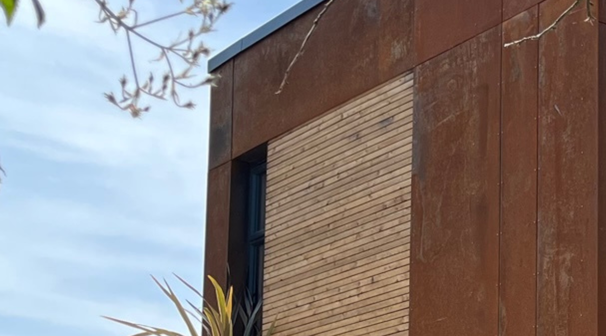 Close-up of the corten steel sheet rich orange patina and oyster grey larch timber panelling on the modular building exterior