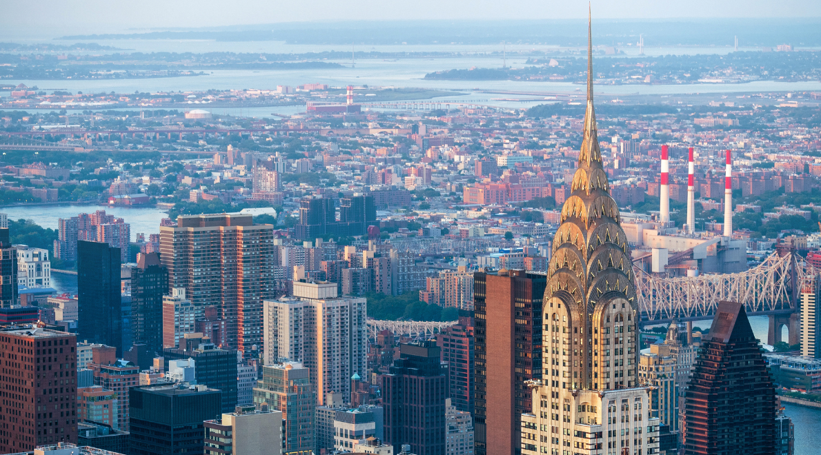 Close-up view of the ornate crown of the Chrysler Building - A pinnacle of Art Deco elegance against the iconic New York City skyline. The intricate spire and radiating arches capture the essence of an era, juxtaposed with the modern urban expanse that stretches beneath, showcasing the timelessness of architectural grandeur.