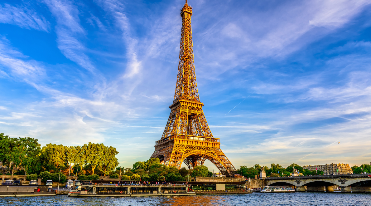 Enchanting view of the Eiffel Tower from water level - A timeless icon rising above the Seine River. The elegant iron lattice structure dominates the scene, framed by the gentle ripples of the water and a passing boat. As the tower pierces the sky, it evokes the romance of Paris, where history, architecture, and the river's embrace converge.
