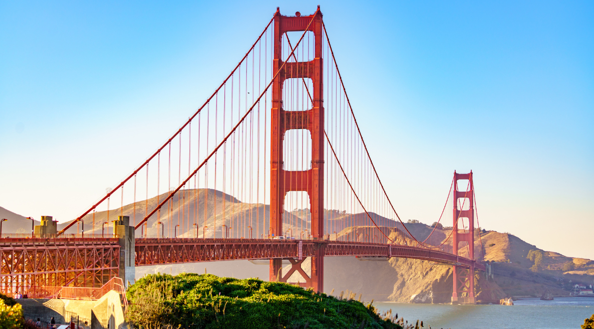 Stunning perspective along the side of the Golden Gate Bridge - A triumphant expanse of international orange steel against the backdrop of San Francisco's bay and skyline. The bridge's soaring cables guide the eye through the frame, illustrating the fusion of nature and human ingenuity in this iconic marvel of engineering.