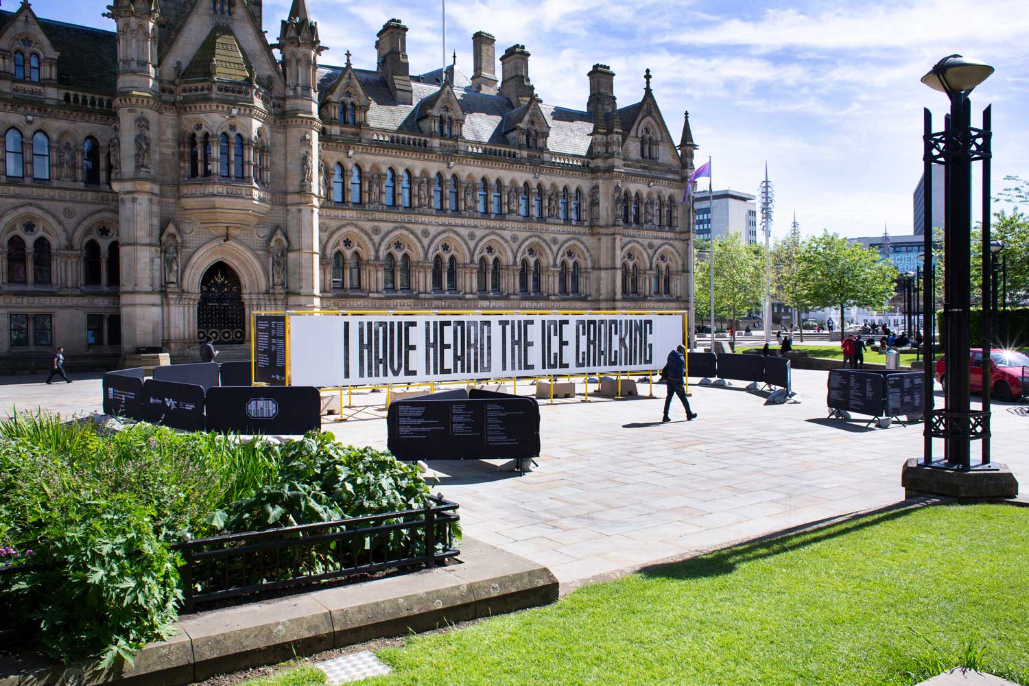 A wide shot of the big, bold yellow mural with Bradford City Hall as a backdrop
