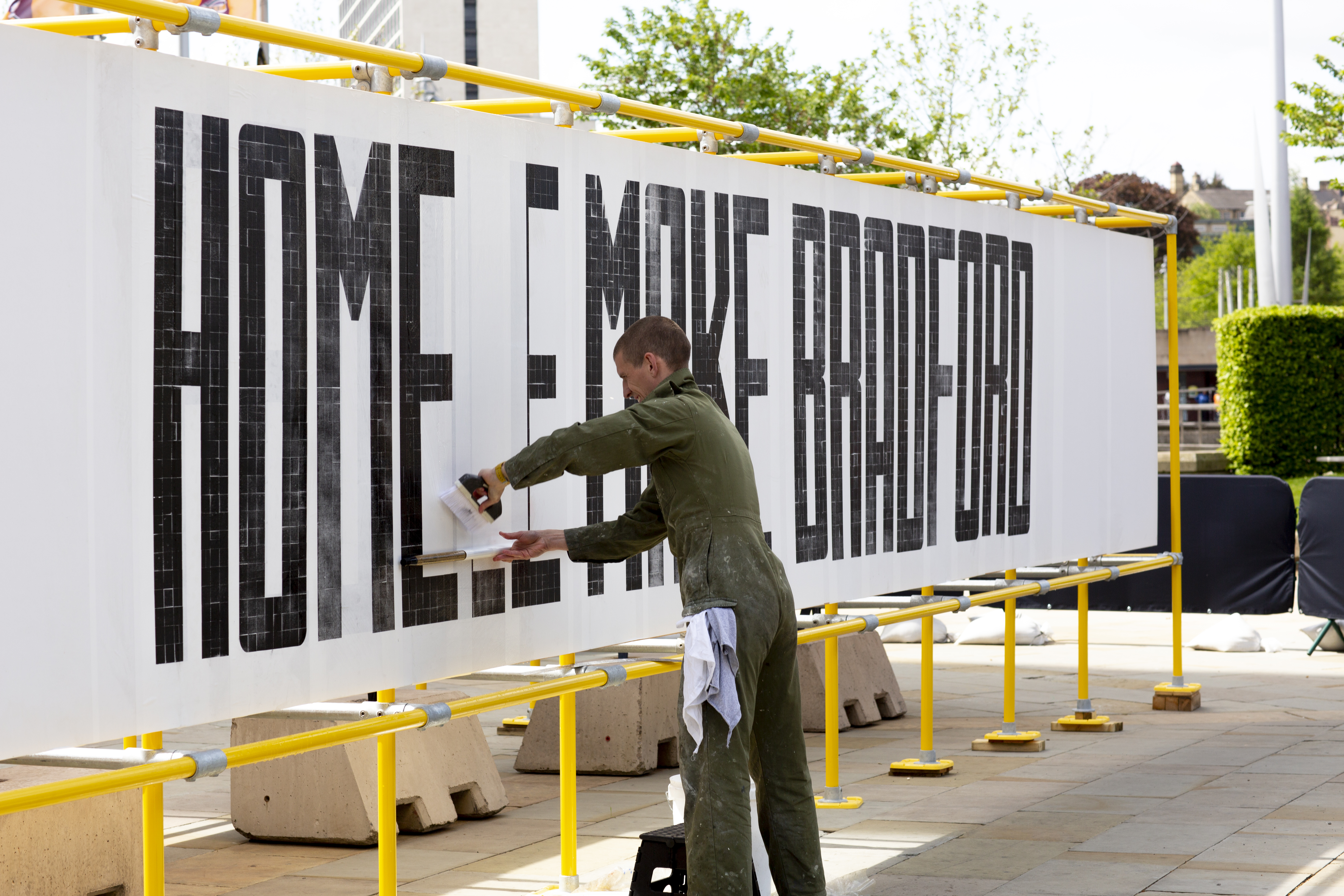 Oli Bentley of the People Powered Press carefully applying the large letterpress prints to the huge yellow frame