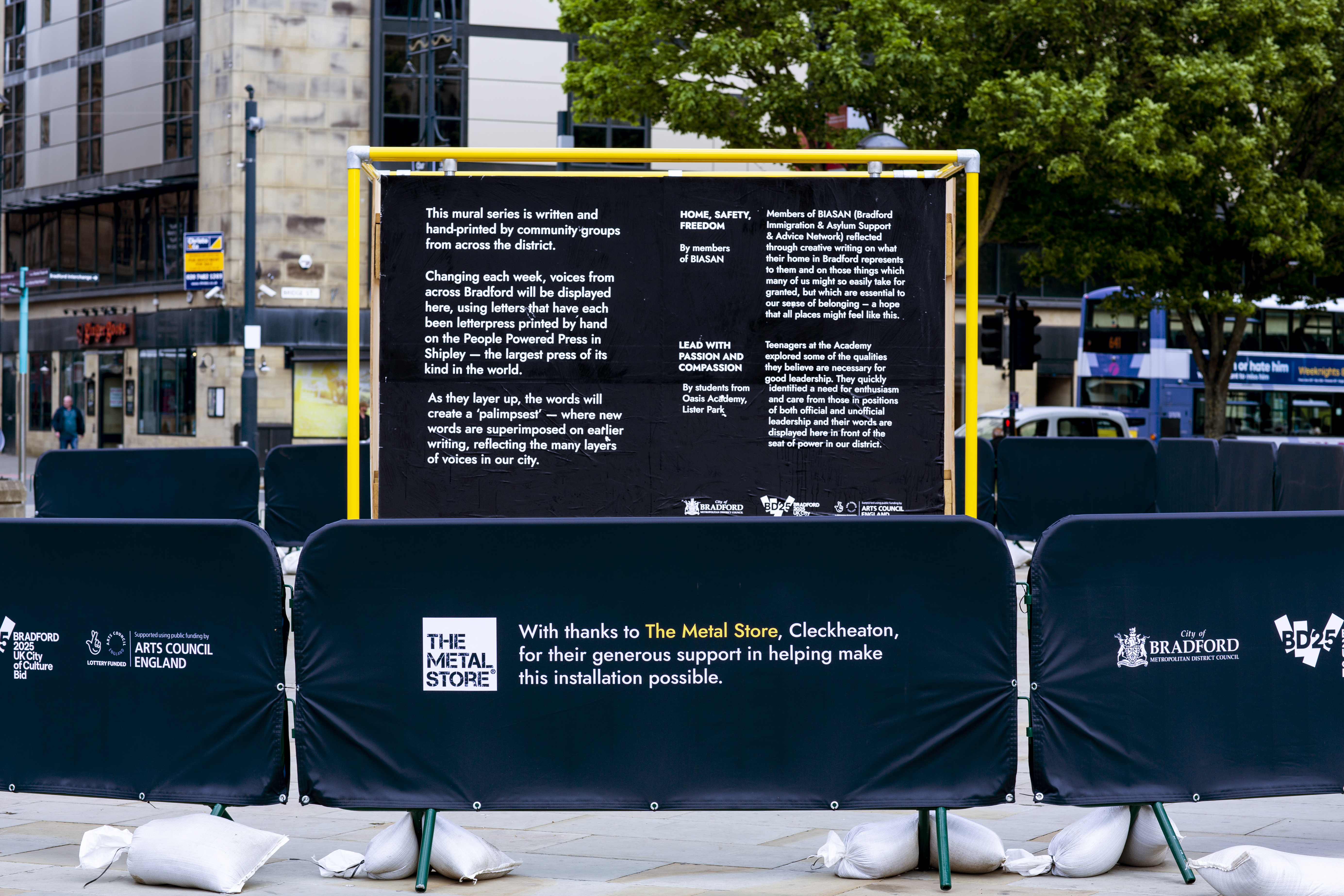 A smaller yellow frame sitting to the side of the large mural showing all partners and sponsors including The Metal Store