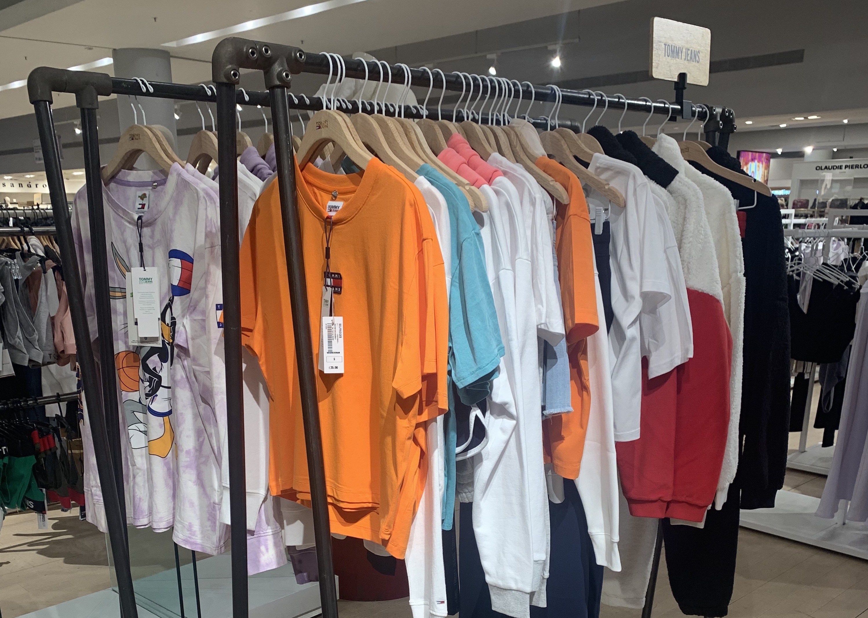 Two mild steel A frame clothing rails side by side displaying a range of vibrant designer t-shirts and jumpers