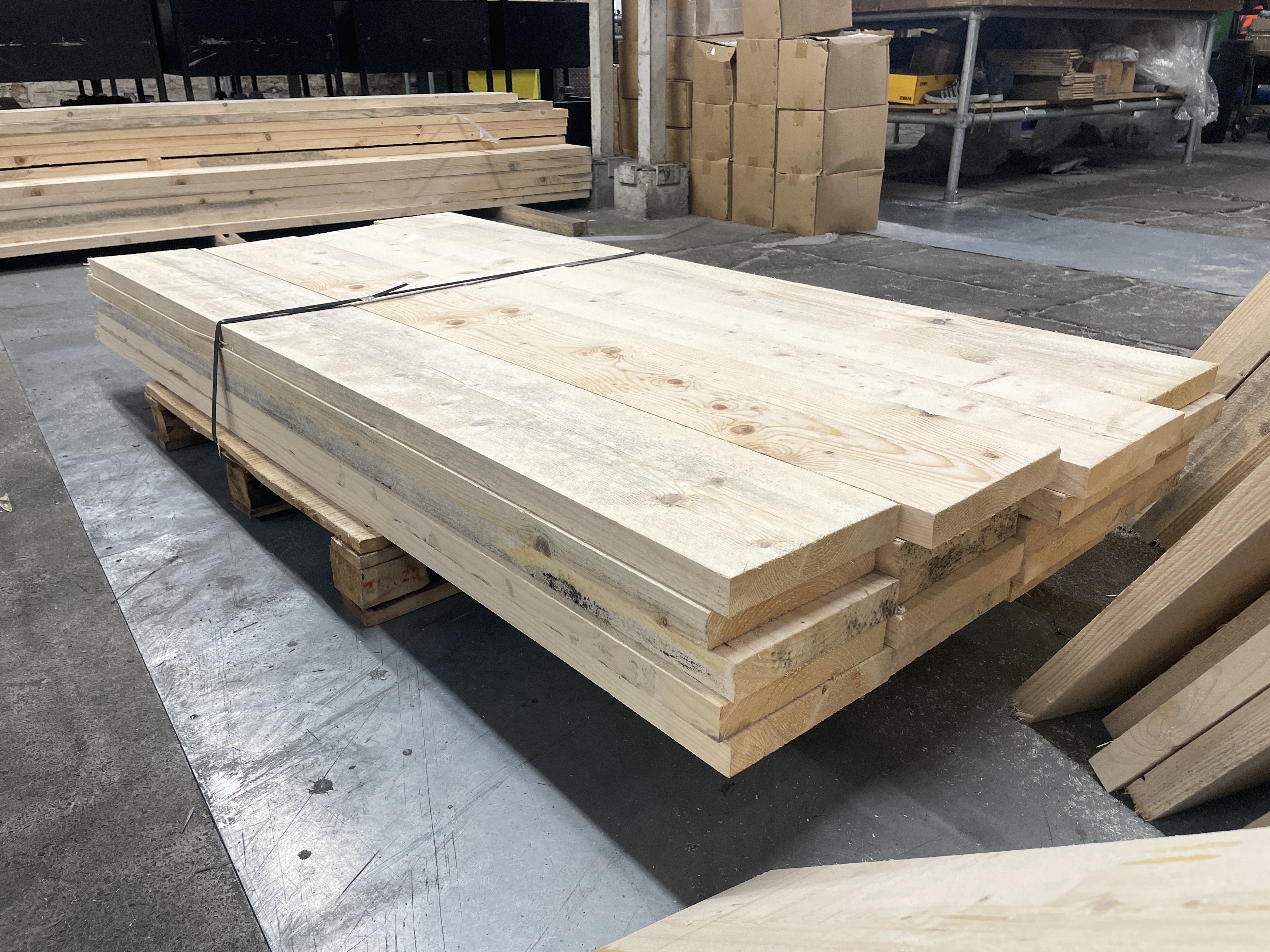 A small bundle of scaffold boards sat on a pallet within a warehouse environment